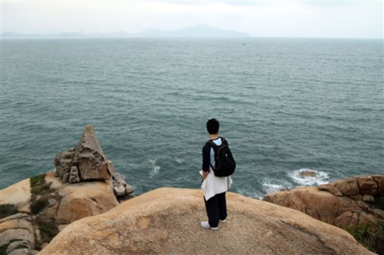 A visitor looks out at the sprawling green waters of the South China Sea as seen from red, granite cliffs in Cheung Chau, Hong Kong. Just eight miles from Hong Kong's Central Pier, Cheung Chau was once a pirate's cove — a place where renegades of the South China Sea stashed their booty. Today, it is a hideout for tourists and locals alike, and makes for a perfect escape from the big city.